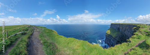 View of the famous Cliffs of Moher  Ireland  taken on a sunny summer day showing blue sky  green grass and ocean