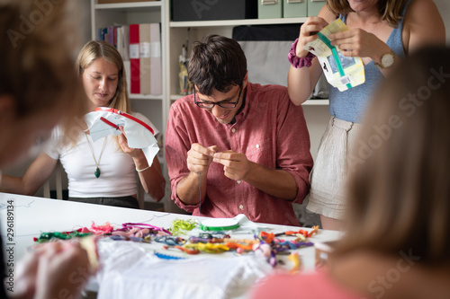 Woman showing a man how to set up his embroidery hoop at a cross-stitching class