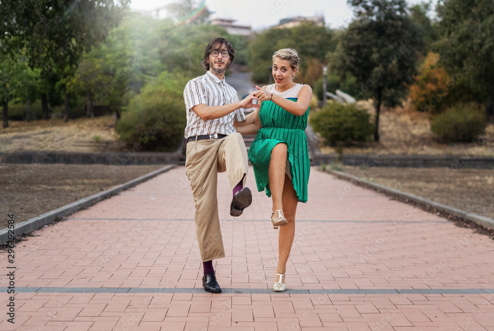 Swing dancers having fun outdoors in the park. Lifestyle concept about people dancing swing music Lindy hop together and having fun! - obrazy, fototapety, plakaty 