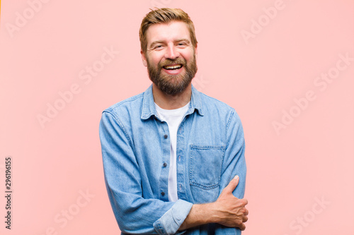 young blonde adult man laughing shyly and cheerfully, with a friendly and positive but insecure attitude photo