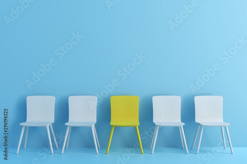 outstanding yellow chair among light blue chair. Chairs with one odd one out in light blue color room. photo