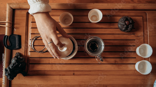 Chinese tea ceremony, girl pours pu-er from gaiwan through strainer in chahai, top view photo