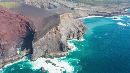 Flying above rocks and deserted surface of vlocano towards green wooded hills. Aeraial of Faial, Azores photo