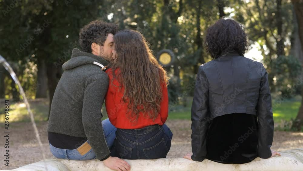 Betrayal, threesome, infidelity.Three people on bench,boyfriend flirts covertly Betrayal, threesome, infidelity.Three people on bench,boyfriend flirts covertly