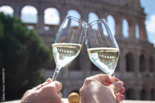 two hands hold a glass of champagne against the backdrop of the Coliseum. Christmas concept Christmas and New Year in Italy