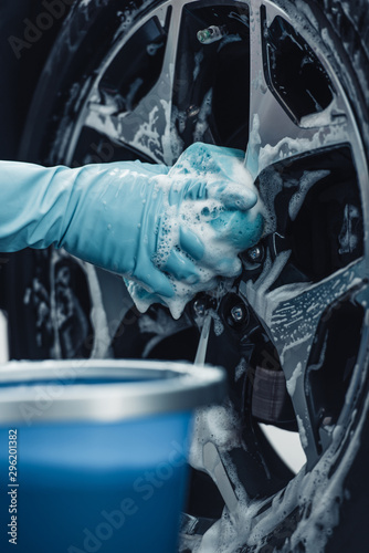 partial view of car cleaner washing wheel with sponge and detergent