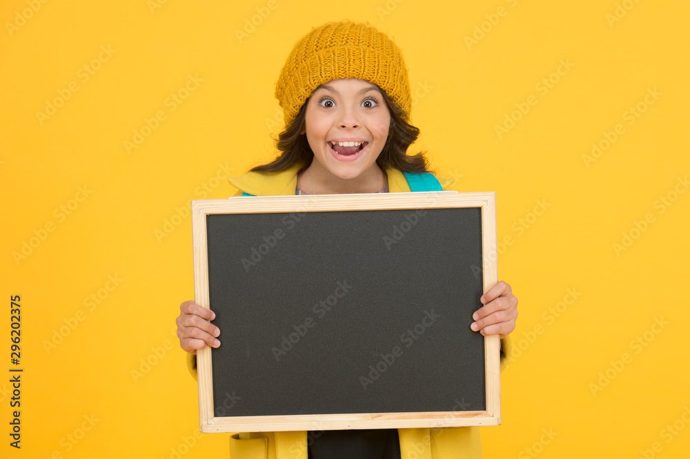 Information education materials. Happy small child hold blank blackboard for education on yellow background. Compulsory primary school education. Public education programme, copy space Information education materials. Happy small child hold blank blackboard for education on yellow background. Compulsory primary school education. Public education programme, copy space
