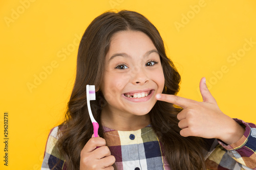 Fototapeta Naklejka Na Ścianę i Meble -  She had her baby tooth out. Happy child show milk tooth removed. Small girl with open mouth and tooth brush. Tooth fairy will visit her