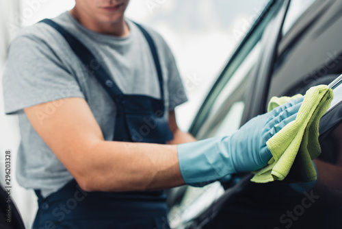 cropped view of car cleaner wiping car with rag