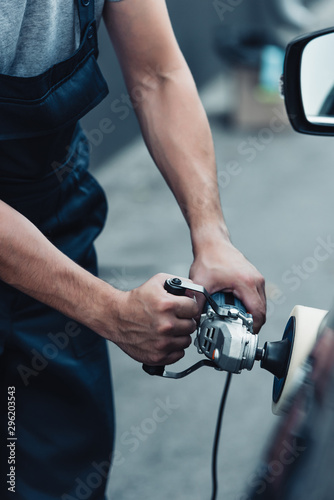 cropped view of car cleaner polishing car door with buffer machine