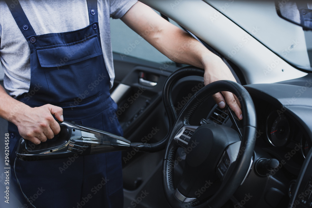 cropped view of car cleaner vacuuming steering wheel