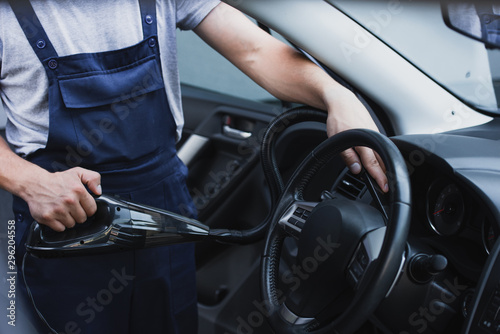 cropped view of car cleaner vacuuming steering wheel