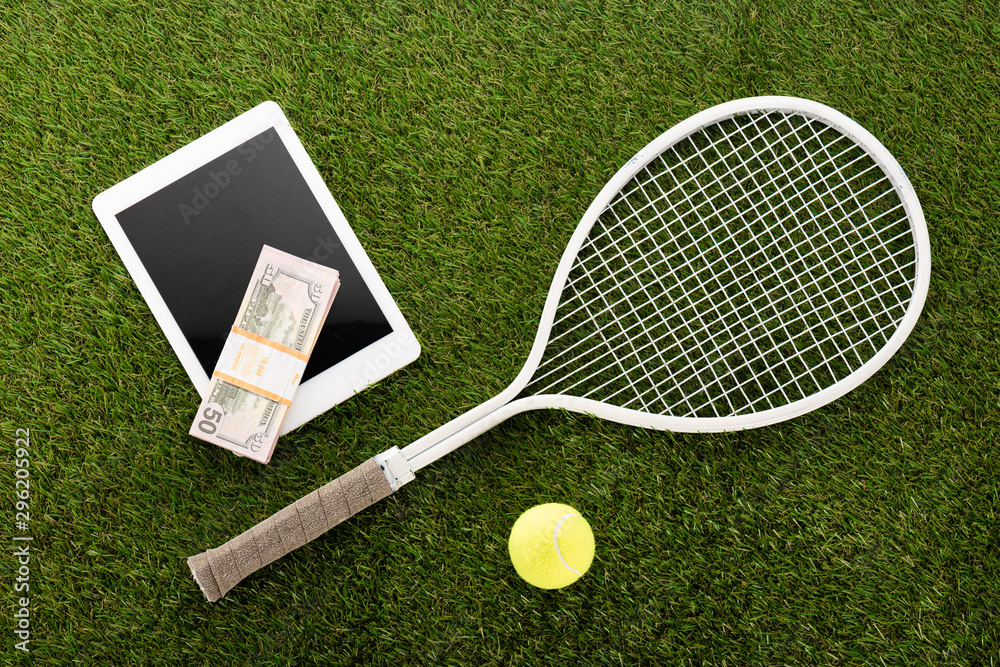 top view of tennis racket and ball near digital tablet and euro banknotes on green grass, sports betting concept