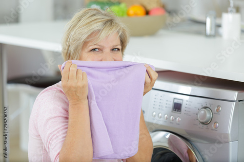 senior washwoman taking of cleaned towels from the washing machine