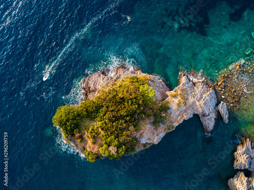 Aerial view of a speedboat hurtling near the island of Sveti Nikola, island of Budva, Montenegro. Jagged coasts with sheer cliffs overlooking the transparent sea. Wild nature and Mediterranean maquis © Naeblys
