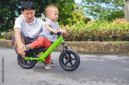 Young father spend time with Cute little Asian 18 months / 1 year old toddler boy child, Dad and son play and have fun with balance bike (run bike), Dad teach son to ride bike, father's day concept