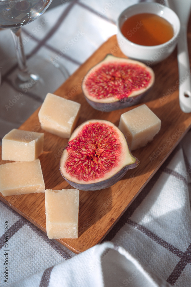 Figs, cheese and honey on a wooden board. rustic breackfast or lunch close up.