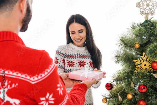 cropped view of bearded man giving present to attractive woman and christmas tree isolated on white