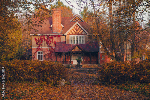 Manor house with trees in autumn colors and fall trees. Old Victorian Haunted House with ghosts. Abandoned house in autumn wood
