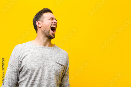 Obraz na plátně young handsome man screaming furiously, shouting aggressively, looking stressed