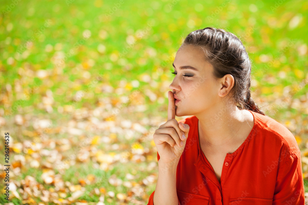 Young beautiful brunette woman has put forefinger to lips as sign of silence Young beautiful brunette woman has put forefinger to lips as sign of silence