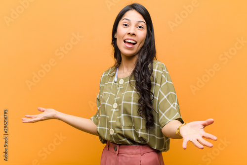 young pretty hispanic woman looking happy, arrogant, proud and self satisfied, feeling like a number one against brown wall photo