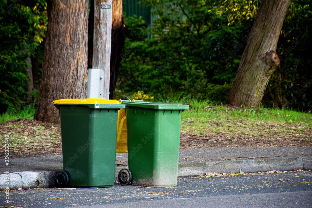 Australian garbage wheelie bins with colourful lids for recycling waste lined up on the street kerbside for council rubbish collection