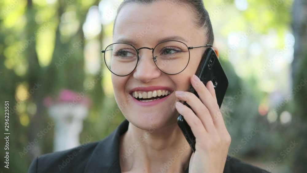 Attractive young business woman with briefcase in black jacket and glasses steps, walks and dances outdoors. Speaks on phone and laughs. Close-up of legs and head. Autumn park, yellow leaves. Attractive young business woman with briefcase in black jacket and glasses steps, walks and dances outdoors. Speaks on phone and laughs. Close-up of legs and head. Autumn park, yellow leaves.