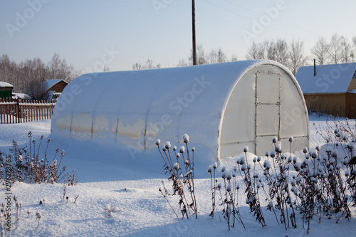Plastic greenhouse in the winter garden. A lot of snow.