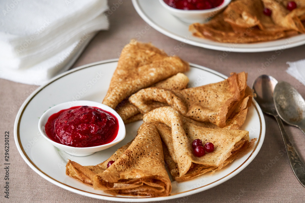 Pancakes with lingonberry sauce on a white plate Pancakes with lingonberry sauce on a white plate