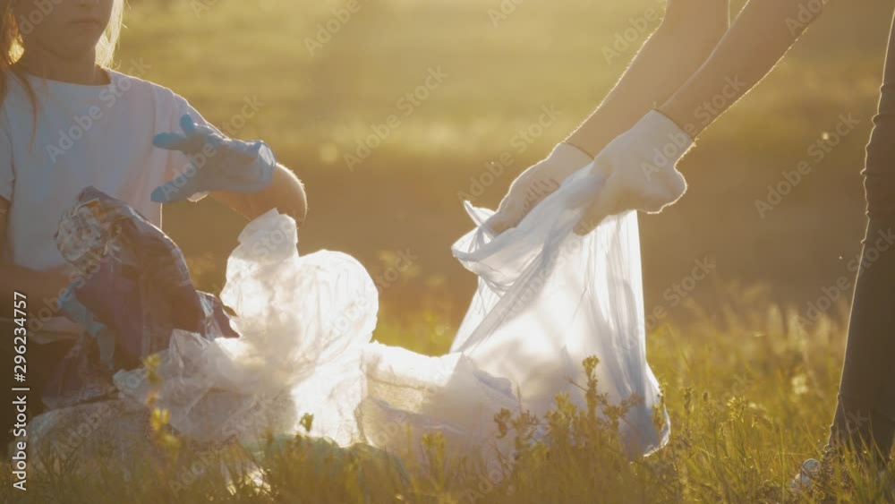 Volunteer team family picking up trash and plastics cleaning the park with a garbage bag. Teamwork and ecology. environment protection pollution problems, plastic waste caring about nature concept. Volunteer team family picking up trash and plastics cleaning the park with a garbage bag. Teamwork and ecology. environment protection pollution problems, plastic waste caring about nature concept.