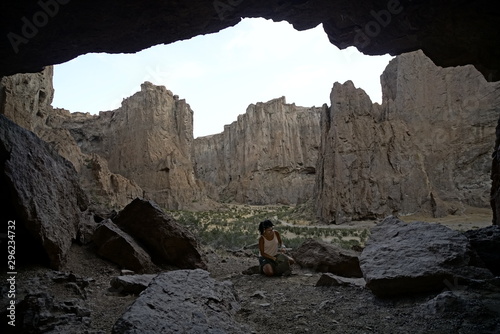 mujer joven revisa su mochila dentro de una cueva de rocas formada en un cañadón del desierto en la Patagonia Argentina.