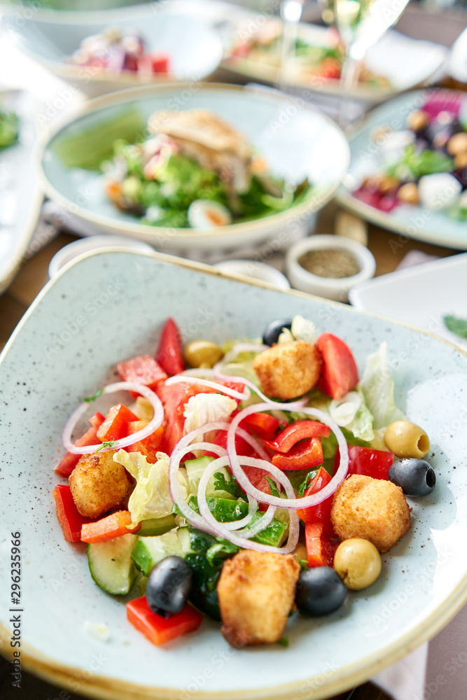 Traditional greek salad with fresh vegetables, feta cheese and olives. Variety of dishes on the table. Various snacks and antipasti on the table. Restaurant menu. Italian cuisine Traditional greek salad with fresh vegetables, feta cheese and olives. Variety of dishes on the table. Various snacks and antipasti on the table. Restaurant menu. Italian cuisine