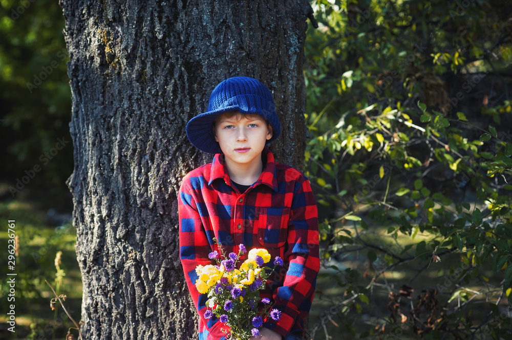 Portrait of a boy with flowers in the Park . A boy in a shirt on a walk . Portrait of a boy with flowers in the Park . A boy in a shirt on a walk .
