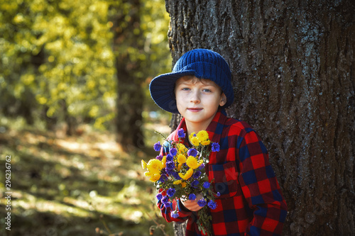 Portrait of a boy with flowers in the Park . A boy in a shirt on a walk .
