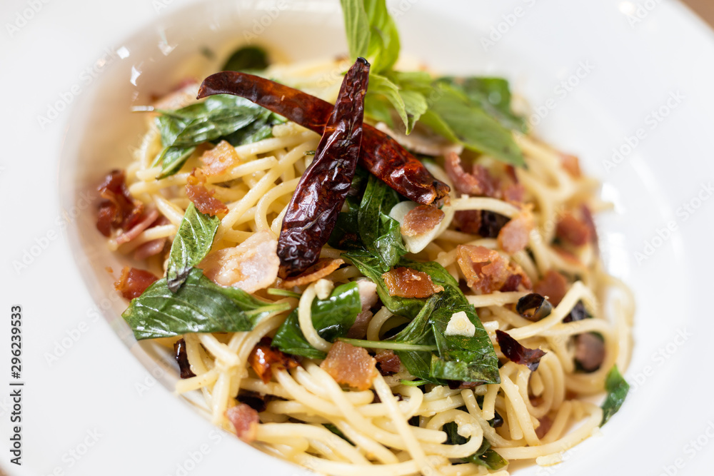 close up Stir-Fried Spaghetti With Dried Chili And Crispy Bacon in a White Plate. close up Stir-Fried Spaghetti With Dried Chili And Crispy Bacon in a White Plate.