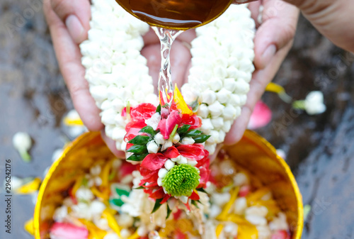 Foto Hand of young woman pour water and flowers on the hands