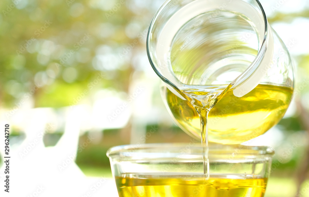 Pouring olive oil in the a glass bowl at stone kitchen and inside green garden view. Prepare for cooking concept. Healthcare and Beauty Concept. Pouring olive oil in the a glass bowl at stone kitchen and inside green garden view. Prepare for cooking concept. Healthcare and Beauty Concept.