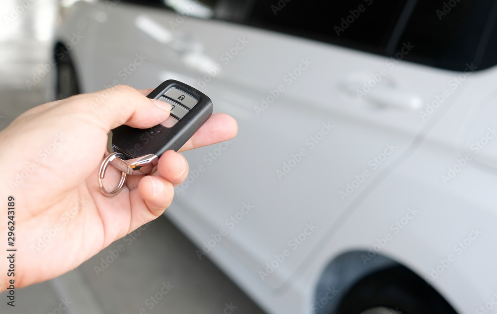 Man hand holding the car remote, he push the remote control to open the car door