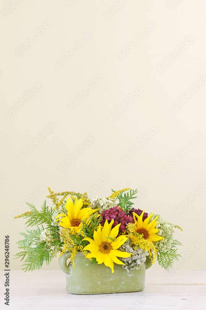 Woman shows how to make floral arrangement with sunflowers and hydrangeas