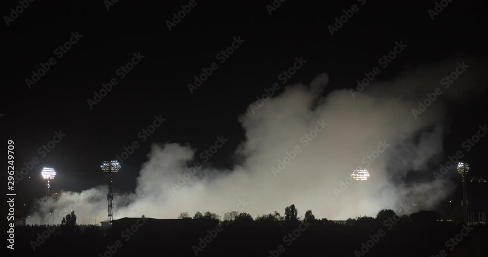 smoke rises above the football stadium at night, total, zoom out smoke rises above the football stadium at night, total, zoom out