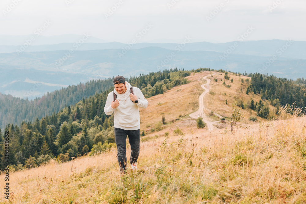 man with backpack hiking by autumn mountains