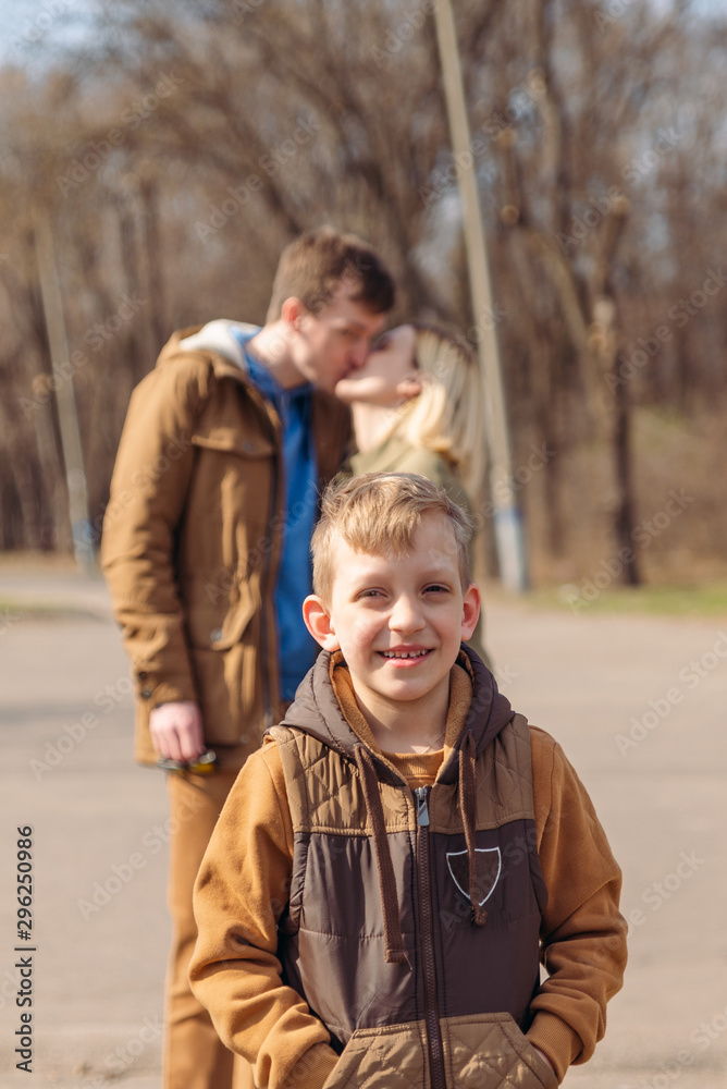 smiling little boy in front. kissing parents on background smiling little boy in front. kissing parents on background
