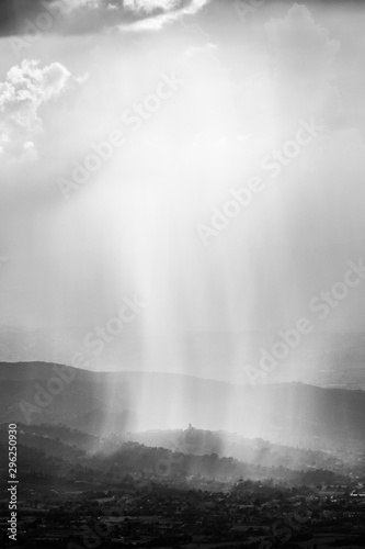 Sunray shines through clouds and rain over the mountains in the middle of shadows