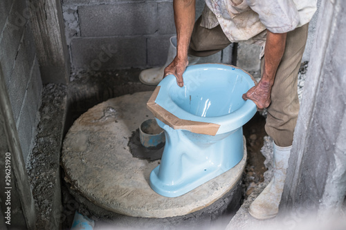 Thai local plumber installing blue toilet in the bathroom