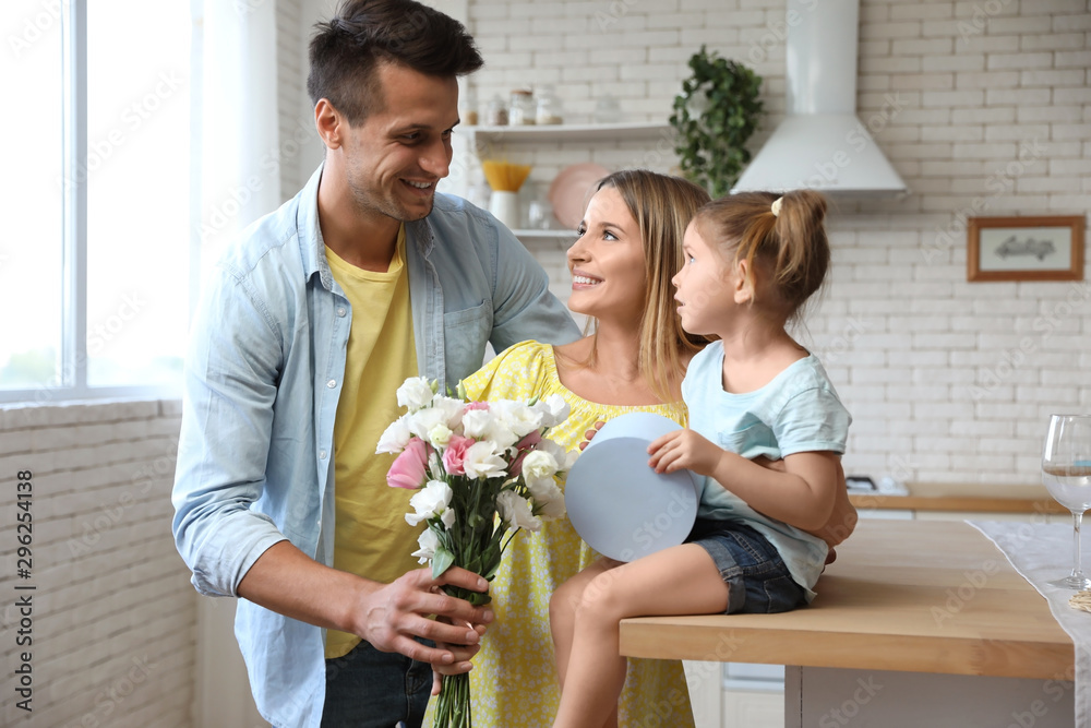 Happy man congratulating his little daughter and wife in kitchen Happy man congratulating his little daughter and wife in kitchen
