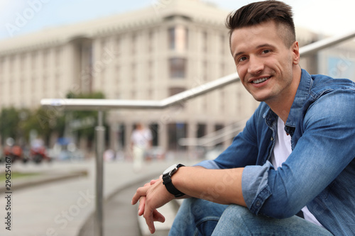 Portrait of handsome young man sitting on stairs outdoors. Space for text Free Download Portrait of handsome young man sitting on stairs outdoors. Space for text - GFXLoad