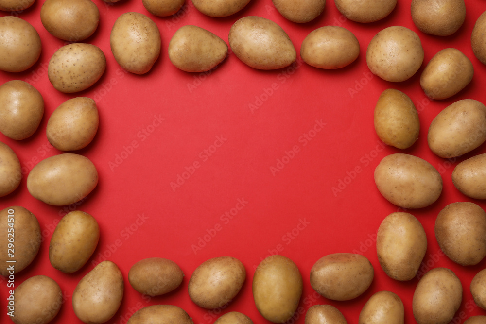 Frame made of raw fresh organic potatoes on red background, flat lay. Space for text Frame made of raw fresh organic potatoes on red background, flat lay. Space for text
