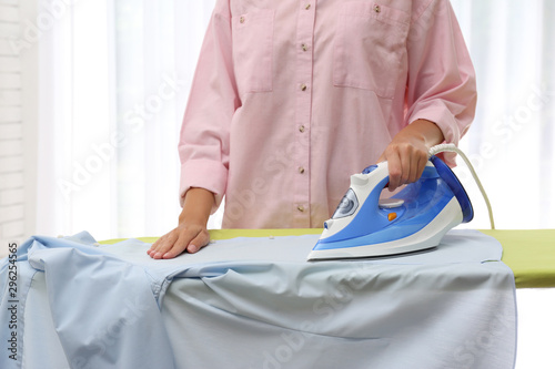 Young woman ironing clean shirt at home, closeup. Laundry day