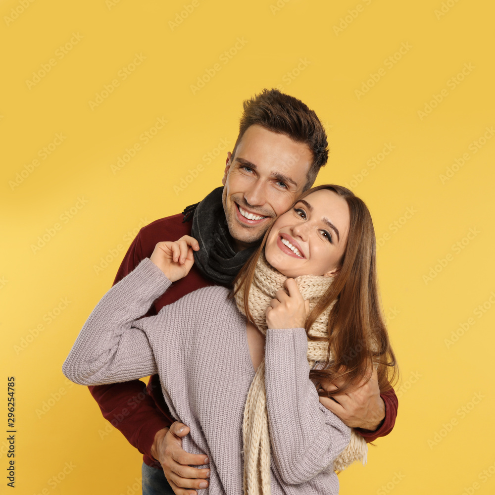 Happy young couple in warm clothes on yellow background. Winter season Happy young couple in warm clothes on yellow background. Winter season